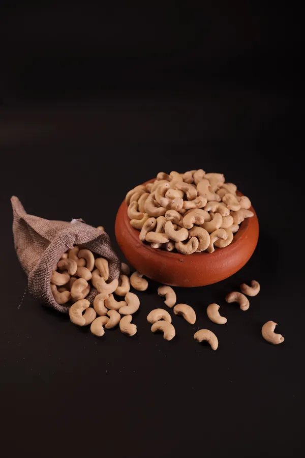 A clay bowl heaped with cashews, more spilling from a jute pouch