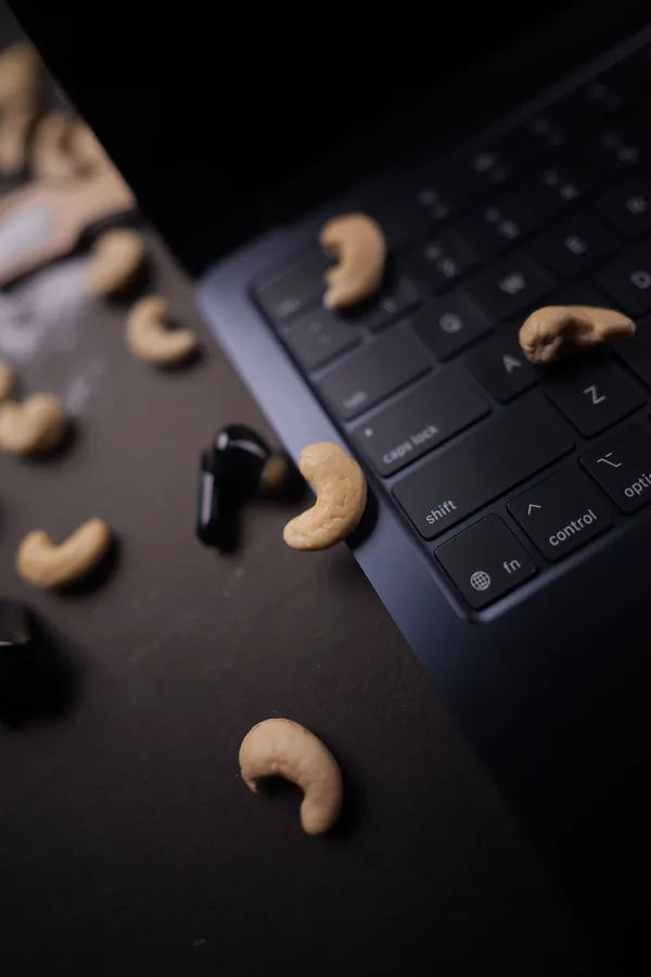 Cashews scattered across a laptop keyboard on a dark desk