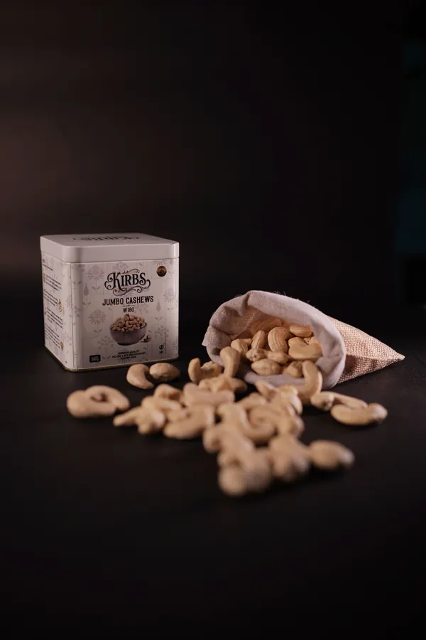 The white Jumbo Cashews tin beside a jute pouch of whole cashews